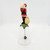 Novelino Inc. Novelino 1992 Christmas Thru The Ages Modern Santa Bell, detailed figurine of Santa Claus in a red suit with a green holly leaf base, a small gift sack, and a dangling holly berry charm.