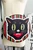The Oblong Box Shop Haunted Holiday Cat Crossbody Purse, Halloween-themed black cat face with green eyes, red tongue, and striped colorful background.