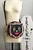 The Oblong Box Shop Haunted Holiday Cat Crossbody Purse, black cat face design with green eyes, red tongue, striped border in black, red, green, orange, and white, on a round black purse with adjustable strap.