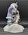 What a Catch! figurine features a Eskimo boy holding fish at his fishing hole with 2 penguins in front of him. The boy is wearing blue pants  and purple jacket holding his fishing rod. The figurine is a hand painted porcelain figurine crafted in Malaysia. Michelle Emblem's figurine is 6.5-inches wide by 7-inches tall and 5-inches deep.