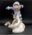 Watch Out figurine features an Eskimo boy chasing 2 penguins in front of him. The boy is wearing blue pants and purple jacket holding his arms out like the penguins. The figurine is a hand painted porcelain figurine crafted in Malaysia. Michelle Emblem's figurine is 8-inches wide by 6.5-inches tall and 4-inches deep.