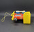 Vintage Fisher-Price 1964 #643 Toot-Toot Engine pull along toy. Wooden cut-out train engine with a rounded boiler that has red paper lithographs on the sides with a blue "sign" marked "Toot Toot" in white. The engine has a yellow plastic front grill and cowcatcher, a yellow plastic cab with a roof, a BLACK wooden smoke stack with small white squares on top, and 4 BLUE wooden wheels with white plastic pistons attached. When pulled, the pistons move and the engine makes a "chug-chug" sound. The model number is marked in small print by the cow catcher. Measures 6-1/4" long, 4-1/4" high, 3-1/4" wide.