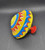 Ohio Art toy spinning top with circus train lithographs that is 5.25-inches diameter. The circus train features conductor pulling 4 cars with elephant, lion, bear and giraffe in the caged train cars. There is a dog with balloons on unicycle following the train.