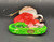 Vintage Kurt S. Adler ceramic hanging Christmas Ornament of Santa sitting on green bench putting on his black boot. The ornament is 3.5-inches tall and 2.25" wide.