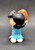 Peanuts Gang Peanuts 2023 Lucy Van Pelt with Football 2.25" Mini Figure, rear view showing Lucy's black hair, blue dress, white shoes, and orange football against a dark background.