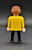 Geobra the German manufacture of Playmobil 1974 Male with brown hair 3-inch tall figure for ages 4+. The figure is wearing a yellow shirt and black pants and shoes. The figure is missing his hat and accessories.