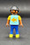 Geobra the German manufacture of Playmobil City Life basic black girl figure that stands 2-inches tall for ages 4+. The figure is wearing a blue shirt with goldfish, peach sleeves, blue pants and has black hair. The figure was exclusive to Germany.