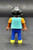 Geobra the German manufacture of Playmobil City Life basic black girl figure that stands 2-inches tall for ages 4+. The figure is wearing a blue shirt with goldfish, peach sleeves, blue pants and has black hair. The figure was exclusive to Germany.