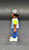 Geobra the German manufacture of Playmobil City Life School Bus black student 2-inch tall figure for ages 4+ from the 5940 City Life School Bus set. The figure is wearing a blue/grey striped shirt with yellow sleeves, blue pants and has black hair.