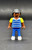 Geobra the German manufacture of Playmobil City Life School Bus black student 2-inch tall figure for ages 4+ from the 5940 City Life School Bus set. The figure is wearing a blue/grey striped shirt with yellow sleeves, blue pants and has black hair.