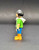 Geobra the German manufacture of Playmobil City Life basic girl figure that stands 2-inches tall for ages 4+. The figure is wearing a green shirt with white horse, white hood, blue pants and has black hair.