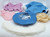 Collection of doll clothing accessories, including a blue denim hat with a white daisy, a pink cardigan, a blue jacket with faux-fur trim, undergarments, and a white faux-fur collar. The collection is for 18-inch dolls.