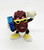 The California Raisins - Boom Box Raisin PVC Toy Figure, colorful cartoon-style figurine of a raisin character wearing yellow sunglasses, yellow sneakers, holding a blue boom box, smiling and making a peace sign.