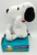 Hasbro Peanuts Snoopy & Friends Gigglin Snoopy plush toy, a white plush dog with black ears and a red collar, sitting on a blue box with text and Snoopy graphic, giving a giggle.