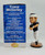 Legends Penn State Trace McSorley Bobblehead, collectible sports figurine of a football player in black jersey and white pants with a white headband, standing on a circular base next to a blue box with player statistics.