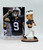 Legends Penn State Trace McSorley Bobblehead, collectible figurine of Penn State football player Trace McSorley in uniform with black eye paint, standing on a brown base with his name, positioned next to packaging featuring an action shot of Trace McSorley in Penn State jersey.