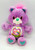 Care Bears - Share Bear (1991), a plush purple teddy bear with a heart-shaped nose, embroidered rainbow and heart design on its belly, and blue heart patches on its feet.