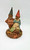 Cairn Studio, LTD Tom Clark Gnomes - First Smile figurine featuring two cheerful gnomes with smiling faces, wearing pointed hats and rustic clothing, displayed on a detailed base that includes natural elements like leaves and bark.