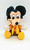 Disney's Mickey's Christmas Carol Mickey Mouse Plush, a soft and cuddly stuffed toy featuring Mickey Mouse dressed as Ebenezer Scrooge with a warm yellow scarf, brown coat, and yellow shoes.