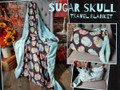 This is an example of a finished (40" x 60") Travel Blanket. "Sugar Skulls" on the front, and "Bella in Seaglass" on the back.  Picture shows the "Travel Handle" upgrade.