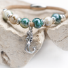 Close-up of cork bracelet with ceramic beads and sterling silver mermaid charm displayed on driftwood - Crabby Mermaid