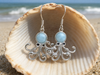 Larimar octopus dangle earrings displayed in a seashell on the beach — genuine Dominican Republic Larimar — Crabby Mermaid