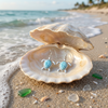 Larimar turtle dangle earrings in an open clam shell with ocean waves in the background — Crabby Mermaid