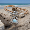 Larimar crab necklace on cork cord with sterling silver accents draped on driftwood with ocean view - Crabby Mermaid
