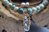 Close-up of sterling silver mermaid charm on glazed teal and beige ceramic bead cork necklace — handcrafted in Florida