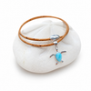Larimar turtle necklace on cork cord displayed on a sand dollar on white background — Crabby Mermaid