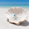 Honu sea turtle sterling silver necklace with indicolite crystal laying in seashell on Florida Gulf Coast beach — Crabby Mermaid