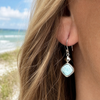 Woman wearing Larimar square drop earring in sterling silver on a Florida beach, close-up