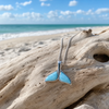 Larimar whale tail necklace in sterling silver draped on weathered driftwood on Florida Gulf Coast beach - genuine Dominican Republic Larimar - Crabby Mermaid