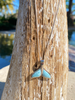 Larimar whale tail necklace displayed on palm tree in Florida sunshine — hand assembled by Crabby Mermaid