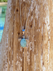 Larimar sea turtle necklace displayed on palm tree with ocean backdrop — hand assembled by Crabby Mermaid