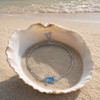 Blue opal sea turtle bolo bracelet in sterling silver displayed in open seashell on Florida Gulf Coast beach — lab-created blue opal turtle charm — Crabby Mermaid
