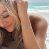 Blue opal sea turtle bolo bracelet in .925 sterling silver worn on model wrist at beach — adjustable 7 to 9 inch bolo toggle closure — Crabby Mermaid