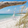 Sterling silver crab necklace with cubic zirconia accents hanging from driftwood on Florida Gulf Coast beach — Crabby Mermaid