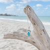 Larimar flip flop pendant necklace in sterling silver hanging from driftwood on Naples Florida Gulf Coast beach - genuine Dominican Republic Larimar - Crabby Mermaid