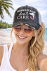 Woman at the beach wearing gray Mermaid Hair Don't Care trucker hat with distressed finish and mesh back — Crabby Mermaid