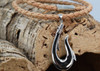 Sterling silver fish hook pendant on braided cork displayed on driftwood showing magnetic clasp ‚Äî Florida artisan jewelry
