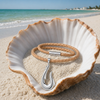 Sterling silver fish hook necklace on braided cork coiled inside large seashell on Florida Gulf Coast beach - Crabby Mermaid