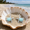 Larimar sea turtle drop earrings in sterling silver displayed in seashell on Florida Gulf Coast beach — genuine Dominican Republic Larimar — Crabby Mermaid