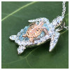 Close-up of sterling silver and rose gold mother and baby sea turtle necklace pendant — aquamarine crystals and two-tone detail — handcrafted in Ireland