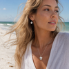 Model wearing sterling silver and rose gold mother and baby sea turtle necklace and matching earrings on Florida Gulf Coast beach — Crabby Mermaid