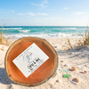 Citrus and mint coconut shell candle on sandy beach with seashells and sea glass - soy coconut wax candle - Crabby Mermaid