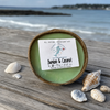 Bamboo and coconut coconut shell candle on beach table between two lounge chairs with tropical drinks - coastal candle gift - Crabby Mermaid