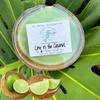 Lime in the coconut half shell coconut candle on monstera leaf with fresh limes and split coconut — green soy coconut wax candle — Crabby Mermaid