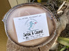 Santal and coconut half shell coconut candle with Crabby Mermaid label resting on tree stump outdoors — all natural soy coconut wax — 5.5 oz