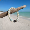 Amazonite gemstone beaded stretch bracelet hanging from driftwood on a Florida Gulf Coast beach
